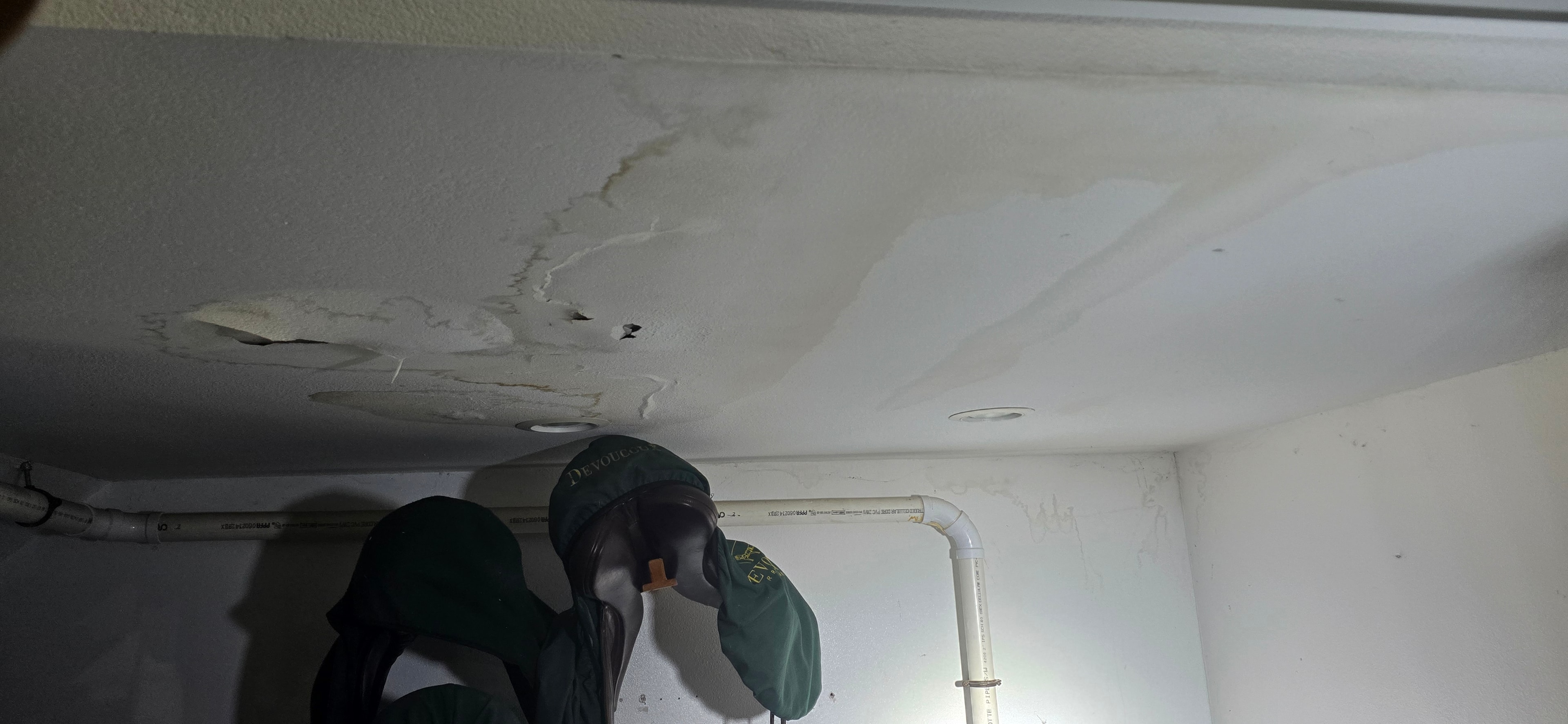 Worker inspecting water damaged ceiling — H&H Construction Services